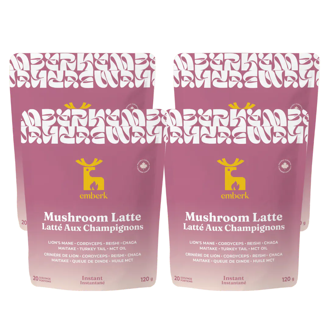 Four stand-up pouches of Emberk Mushroom Latte shown side by side on a plain white background. The packaging is dusty pink with a white patterned top band, a yellow emberk deer logo, and white text.